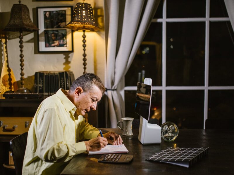 focused man taking notes in planner during remote work at home at night
